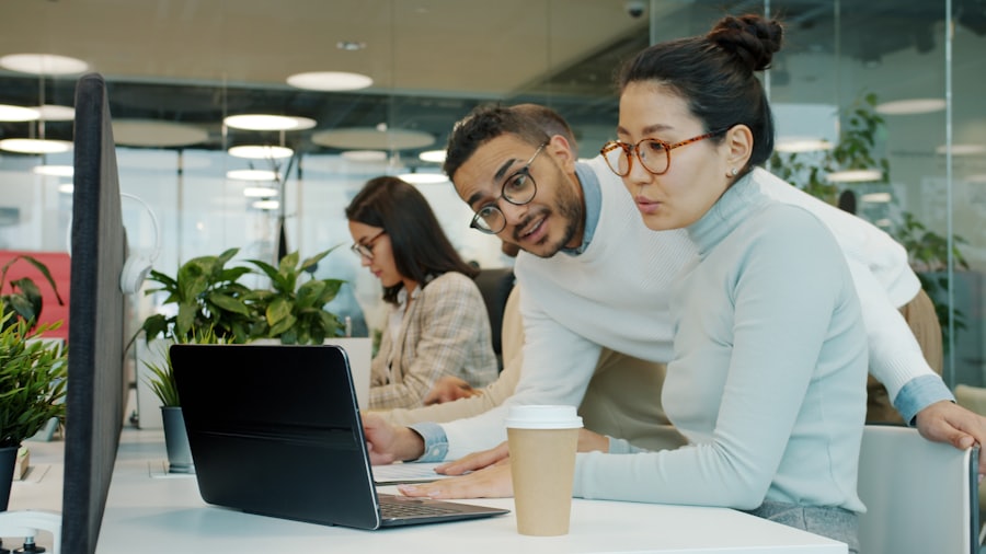 A person working at a laptop with a colleague, reviewing work together