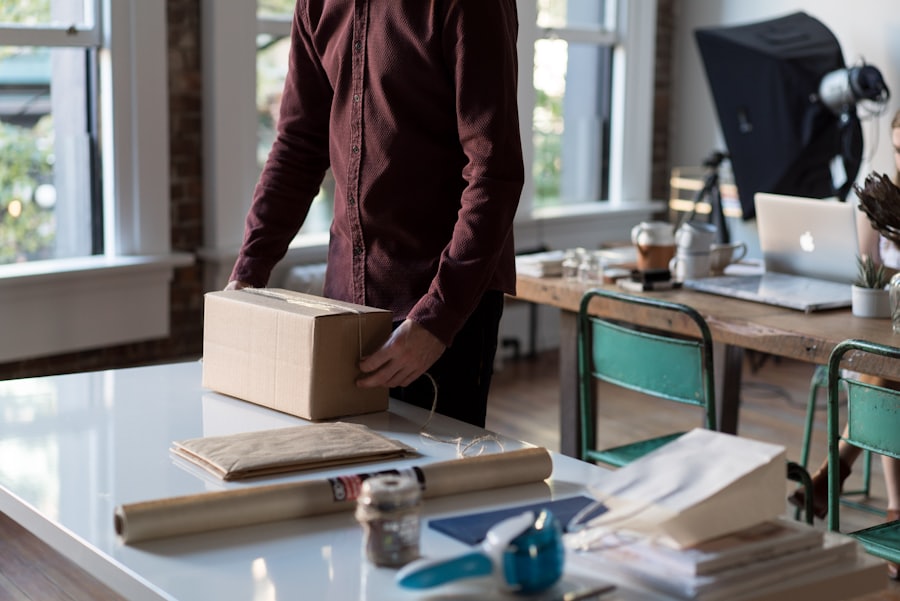 A small-business owner packing a customer order into a cardboard box at their desk