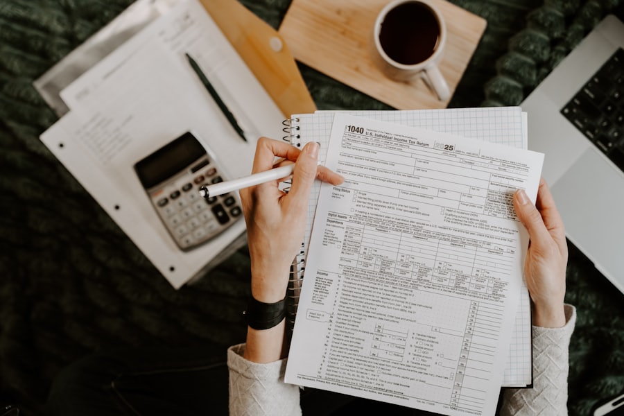 A small business owner reviewing an invoice and running the figures on a calculator beside a laptop.