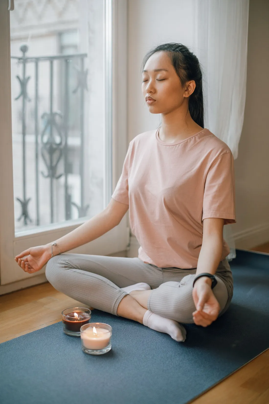 A woman sitting near candles while meditating