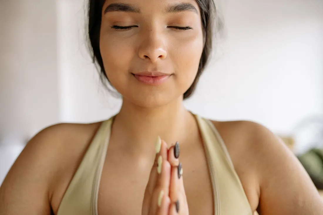 A close-up of a woman meditating with her eyes closed