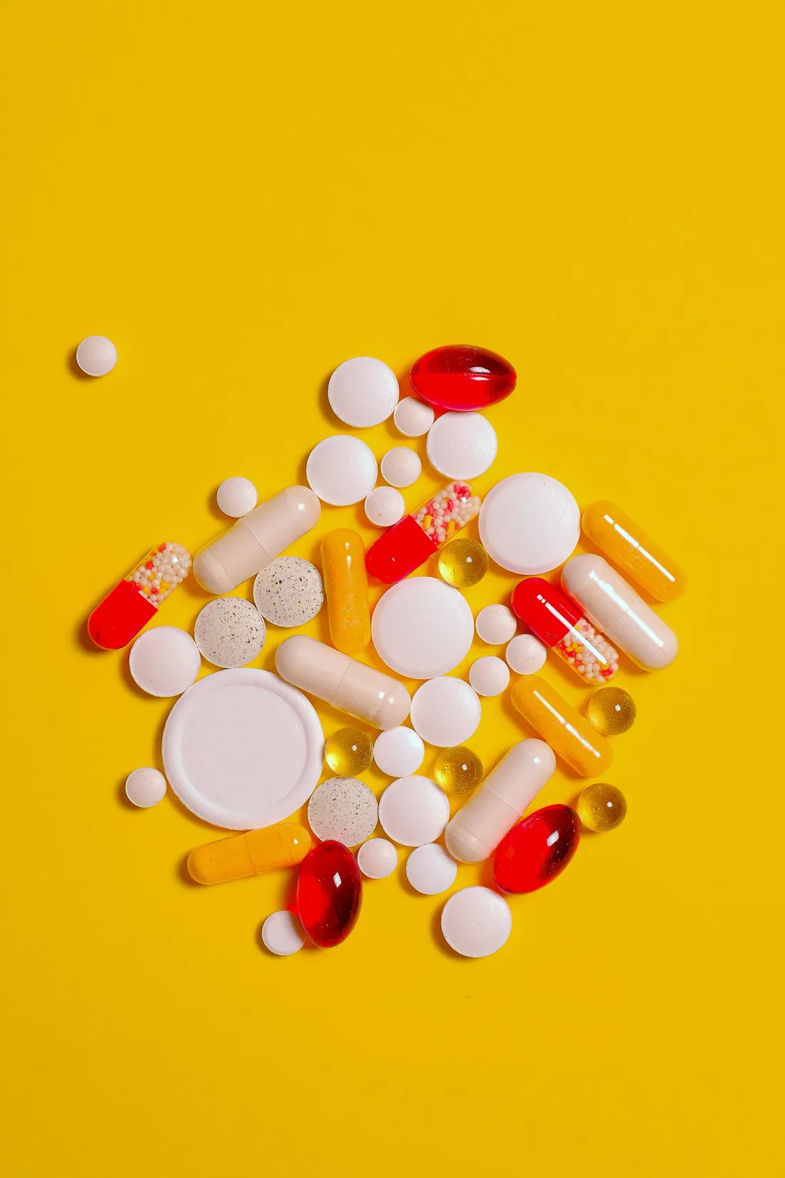 A supplement capsule resting on a yellow surface