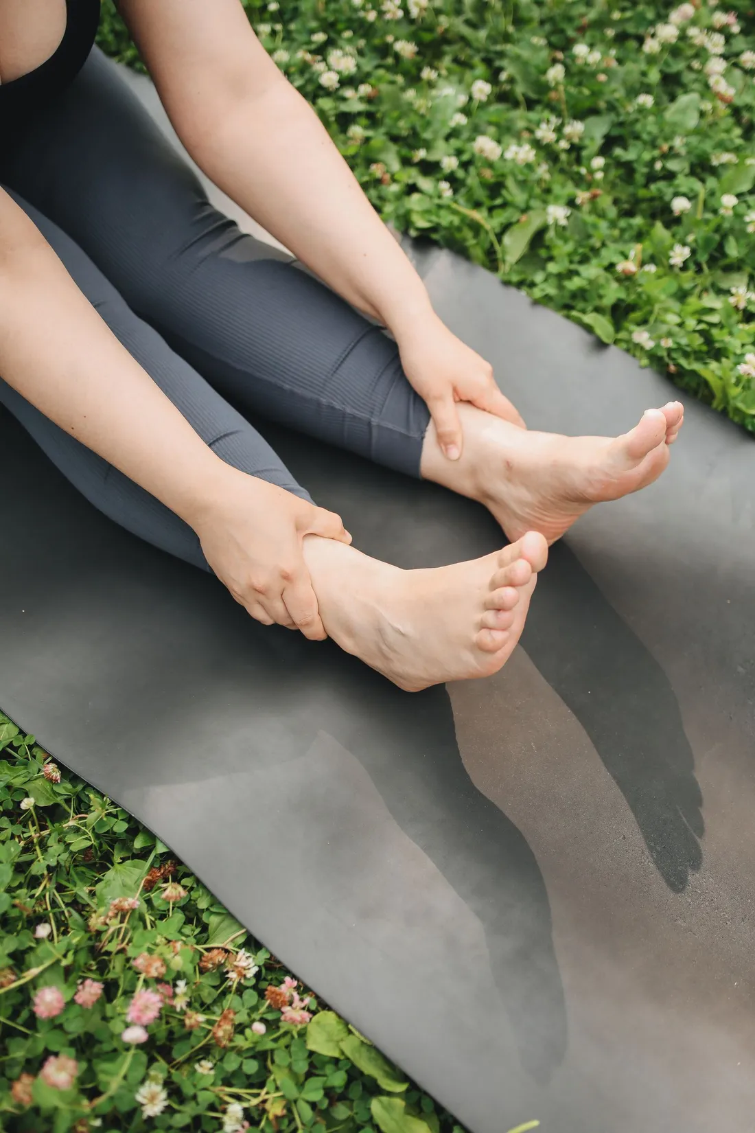 A person sitting on a yoga mat outdoors