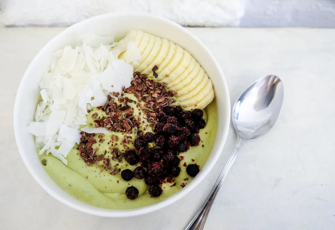 A green smoothie bowl topped with fruit