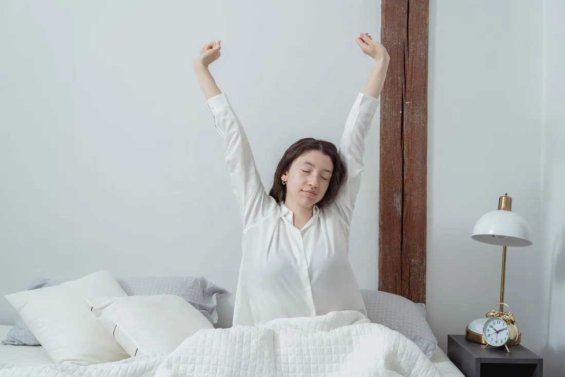 A sleepy woman waking up in bed in the morning light
